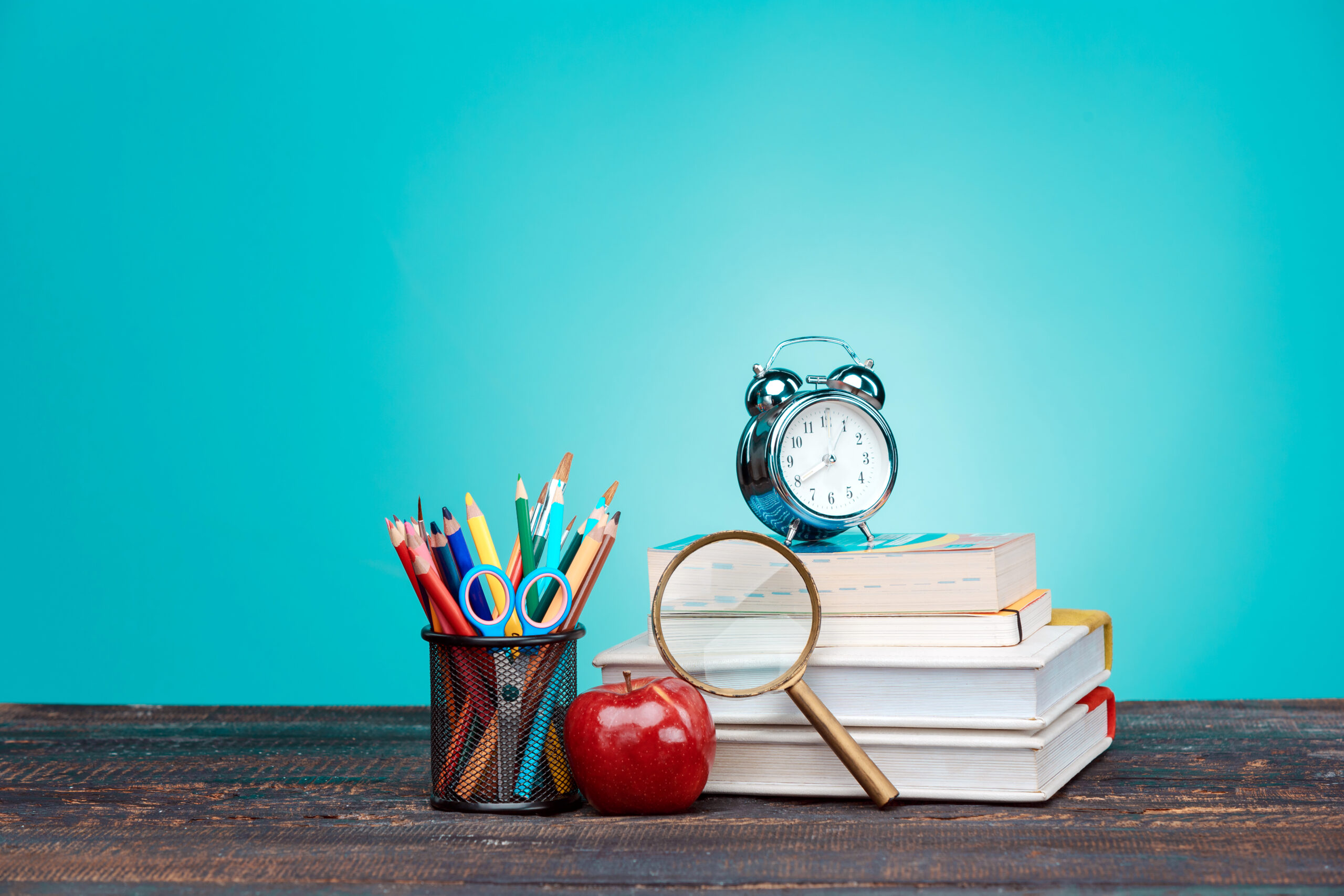 Back to School concept. Books, colored pencils and clock Back to School concept.School Books, colored pencils and clock on blue background