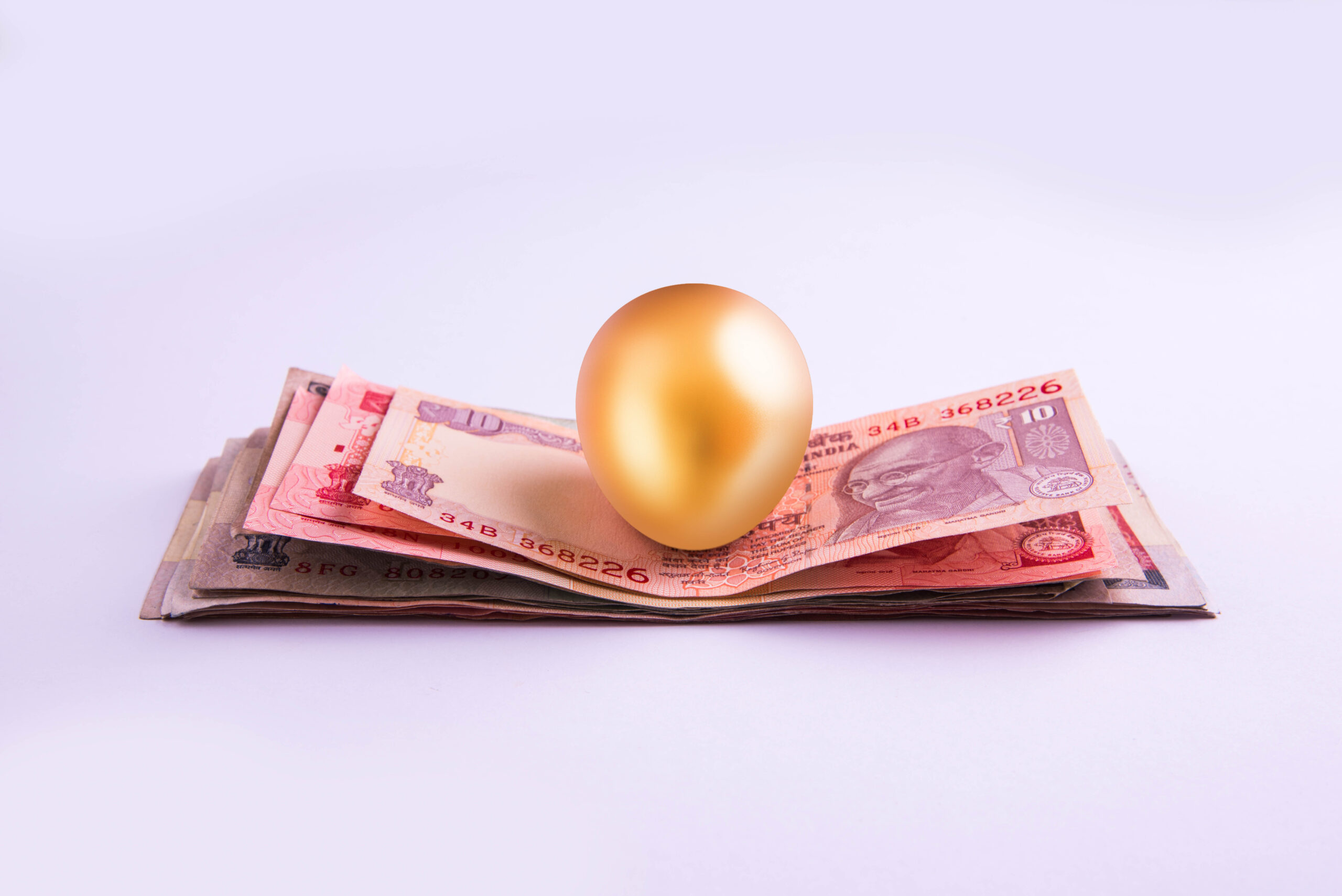 A gold egg on a pile of indian currency notes A gold egg on a pile of indian currency notes